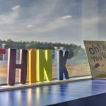 A Think letter sign with "Oh! The Places You'll Go" book on a window sill.